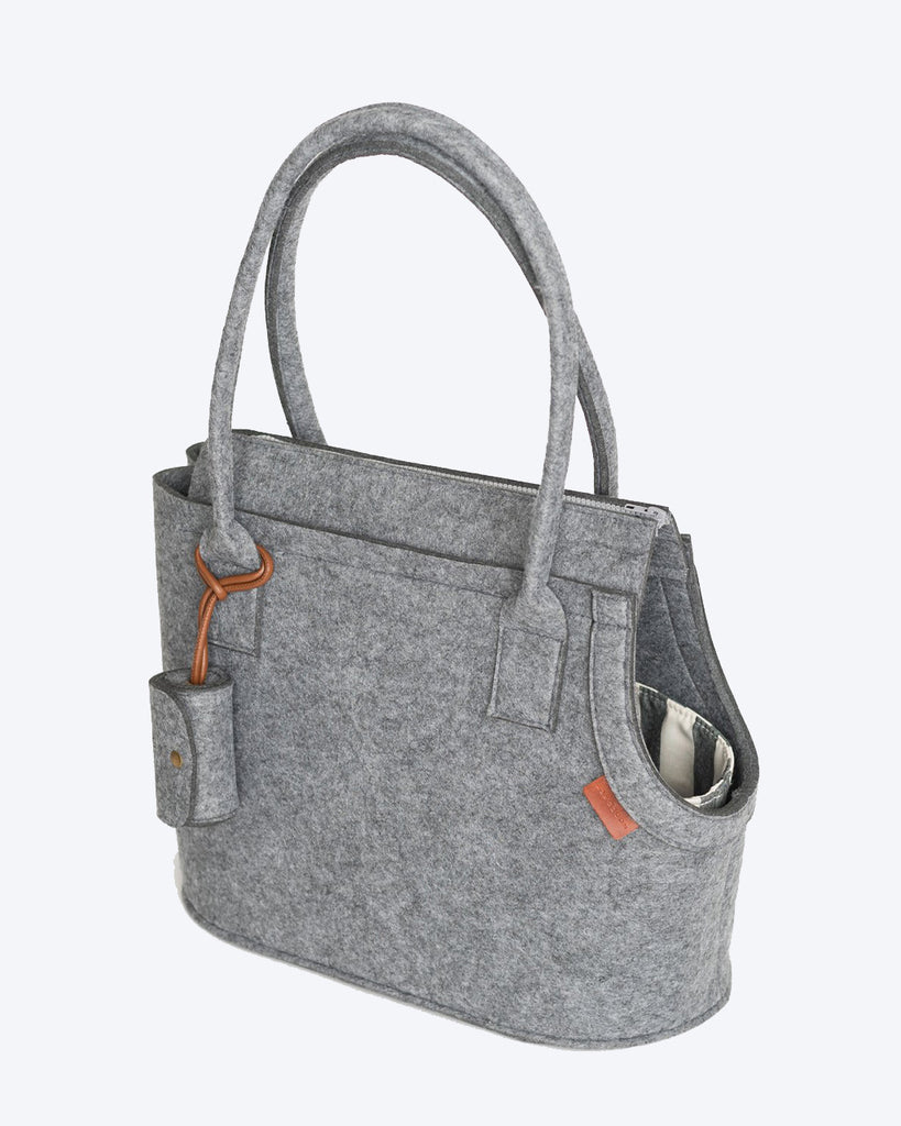 Grey pet carrier with attached poop bag holder. Striped canvas inside.