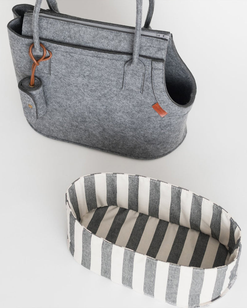 Grey pet carrier with attached poop bag holder. Striped canvas inside.